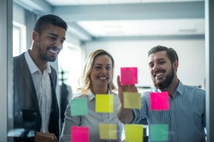 Colleagues looking at sticky notes in an office.